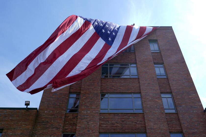 A giant American flag is unfurled on Lisner Hall on the campus of George Washington University in Washington, Friday, May 3, 2024, as demonstrators protest the Israel-Hamas war. (AP Photo/Susan Walsh)