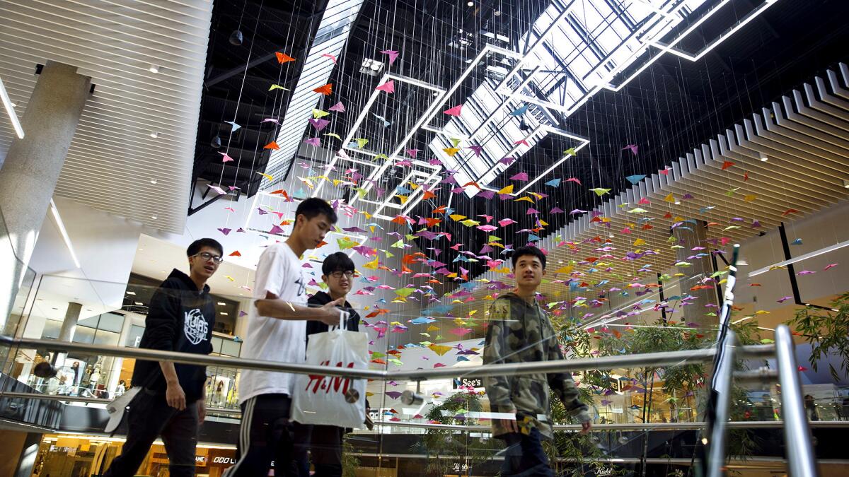 Shoppers walk past paper butterflies hanging inside the Westfield Santa Anita shopping mall in Arcadia. The mall has brought in a variety of Asian retailers and restaurants to appeal to the local community as well as tourists.