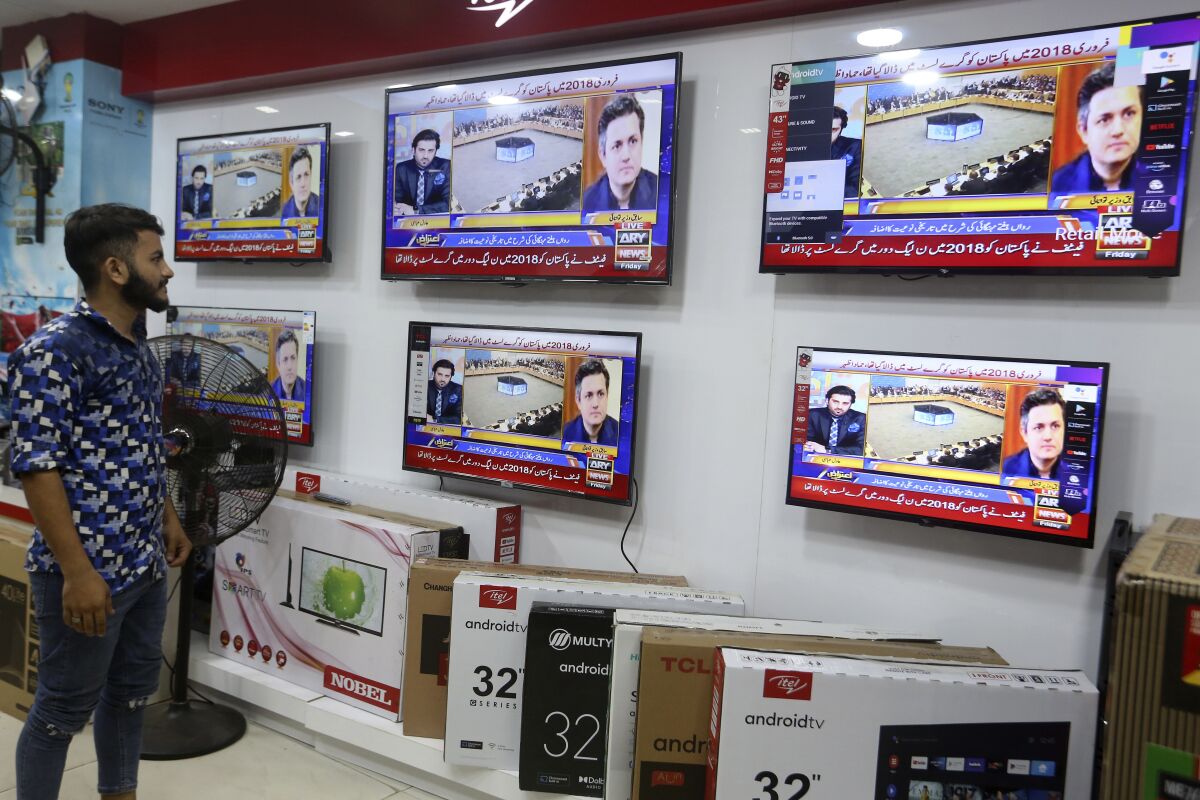 A Pakistan watches news channel flashing news regarding FATF decision, at a market in Karachi, Pakistan, Friday, June 17, 2022. An international watchdog said Friday it will keep Pakistan on a so-called "gray list" of countries that do not take full measures to combat money-laundering and terror financing but raised hopes that its removal would follow an upcoming visit to the country to determine its progress. (AP Photo/Fareed Khan)