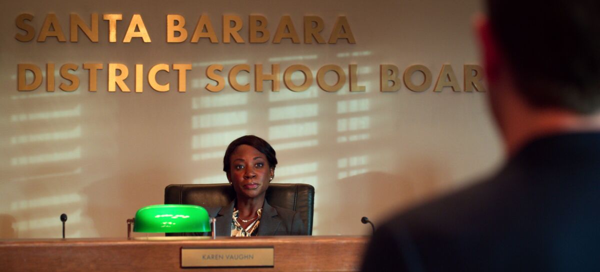 A woman sits in a chair under a sign that says Santa Barbara District School Board.