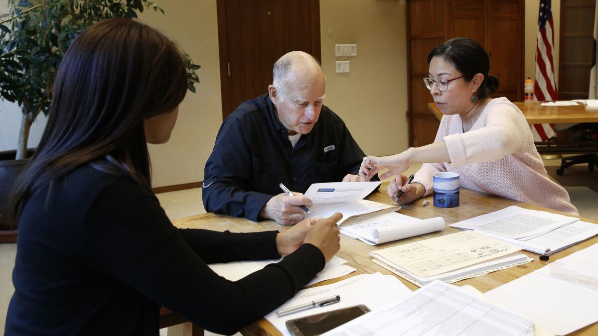 Gov. Jerry Brown reviews a measure with staff members Camille Wagner, left, Graciela Castillo-Krings at his Capitol office on Sept. 30.