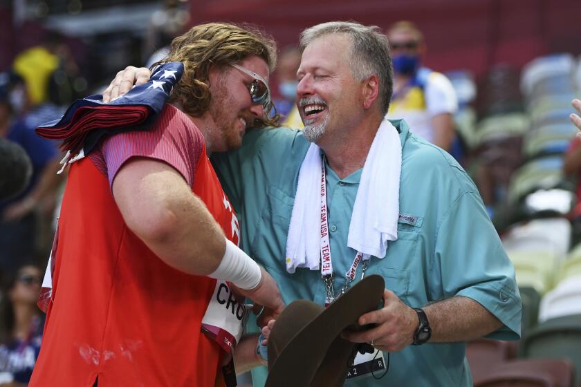 Ryan Crouser, of United States, holds a sign while celebrating winning the gold.