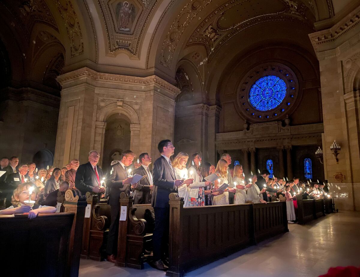 Hundreds of people light candles in pews inside a church