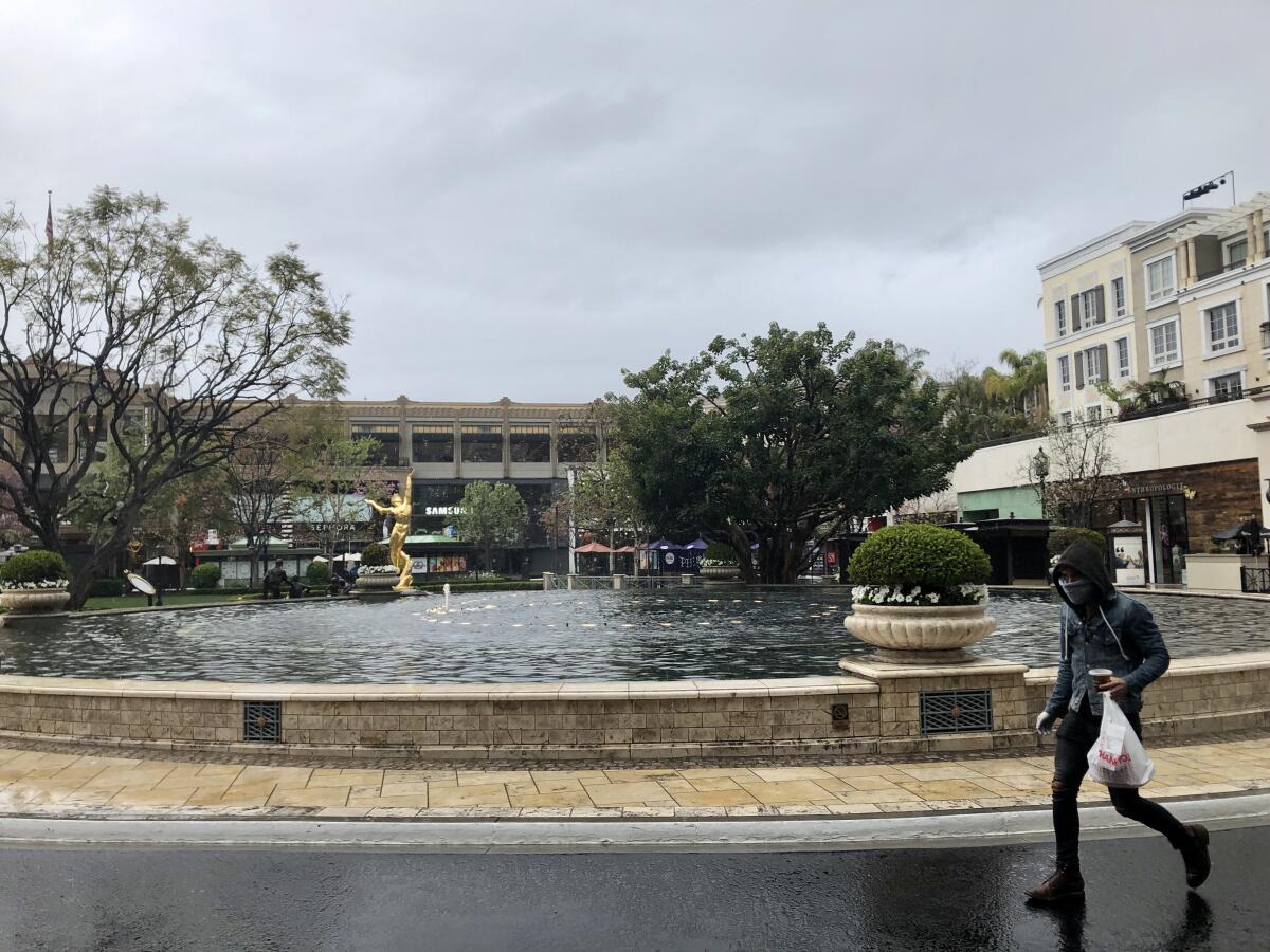 A person braves the rain to make a food pickup at the Americana on Brand on April 7.