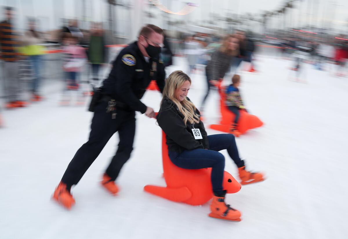 Lt. Brian Smith pushes public information officer Jennifer Carey on a seal sled during the "Skate With HBPD" event. 