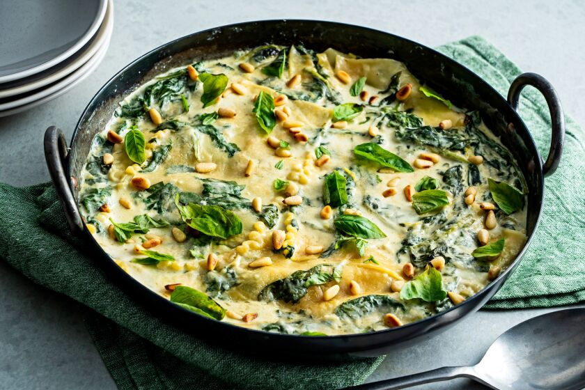 A large skillet contains creamy spinach and zucchini lasagna. 