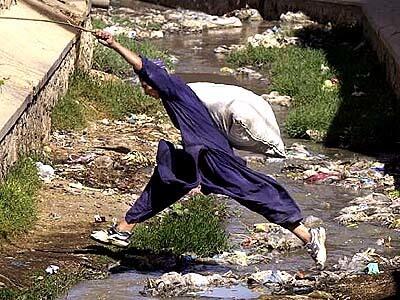 With his scavenger's sack bulging with the morning's collection, Abdul Hakim, 15 leaps over a sewer canal in Quetta, Pakistan.