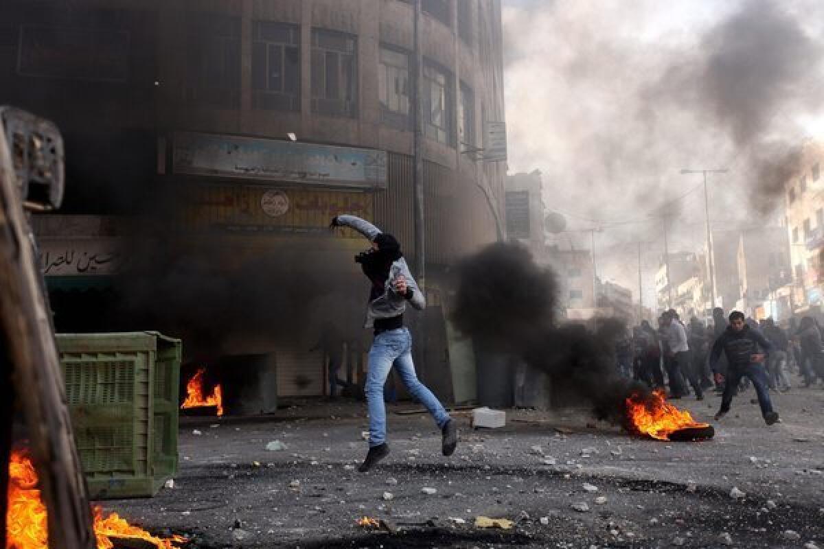 A Palestinian youth throws a stone as protesters clash with Israeli riot police in the West Bank city of Hebron.