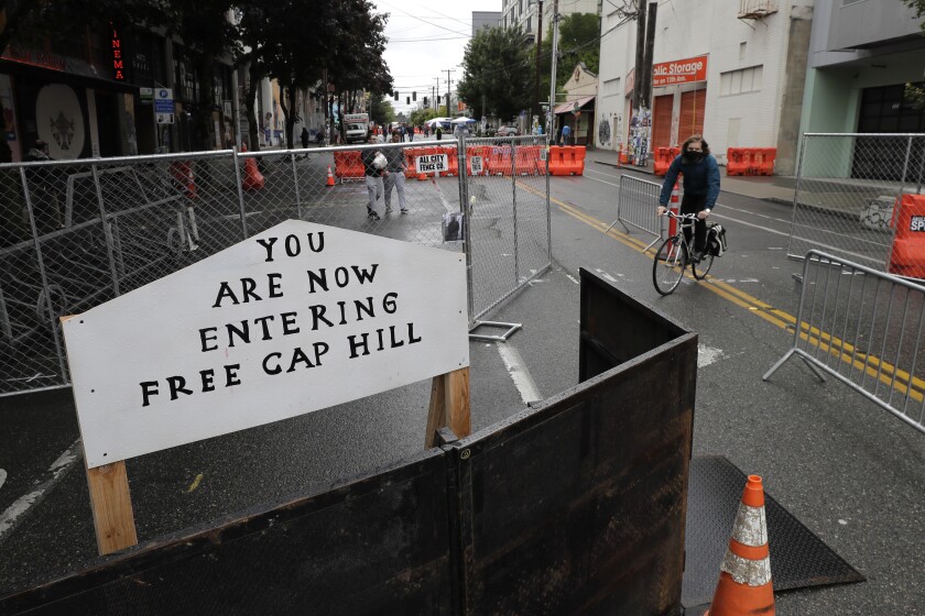 A sign reads "You are now entering free Cap Hill" in Seattle.