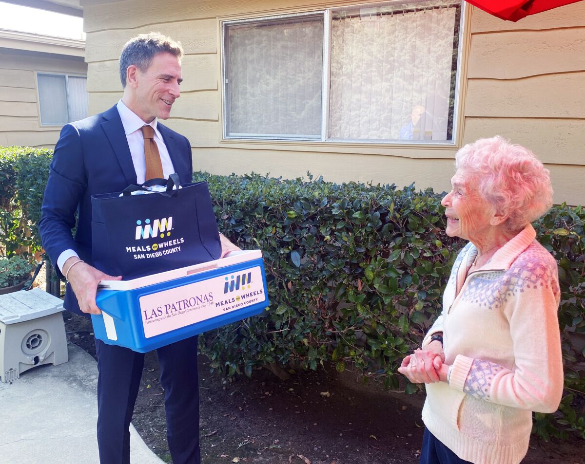 Brent Wakefield delivering lunch to 101-year-old Barbara Bartosik outside her home in Pacific Beach.