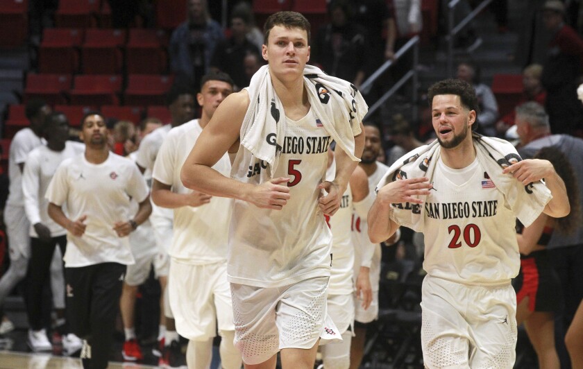 The Aztecs' Yanni Wetzell (left) and Jordan Schakel leave the court with teammates after the Aztecs beat Cal Poly 73-57 at Viejas Arena on Dec. 28.