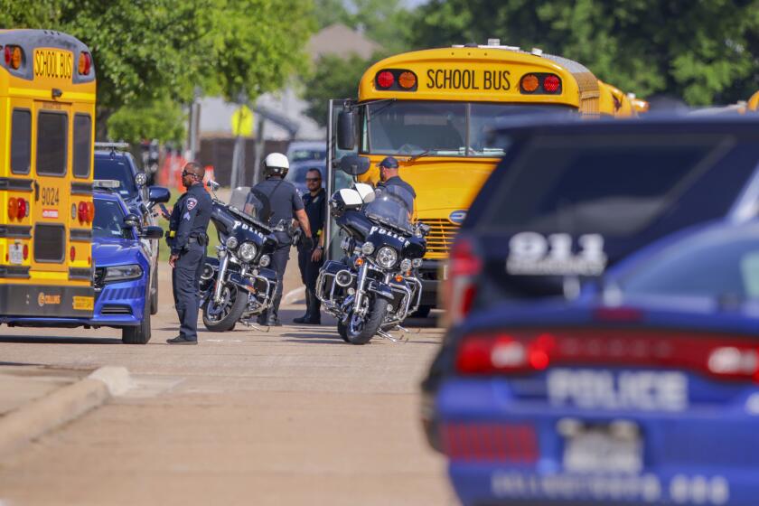 Police officers prepare to escort students to be reunited with their families at Arlington Bowie High School after the school was placed on a lockdown due to a suspected shooting outside the school building, Wednesday April 24, 2024, in Arlington, Texas. (AP Photo/Gareth Patterson)