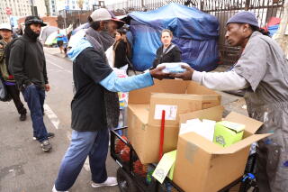 Community Ambassador Crushow Herring gives a hygiene bag to a homeless man in Skid Row.