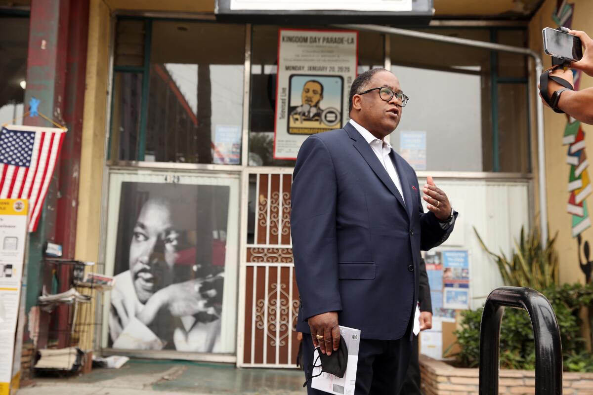 Mark Ridley-Thomas speaks outdoors near a photo of Martin Luther King Jr. 