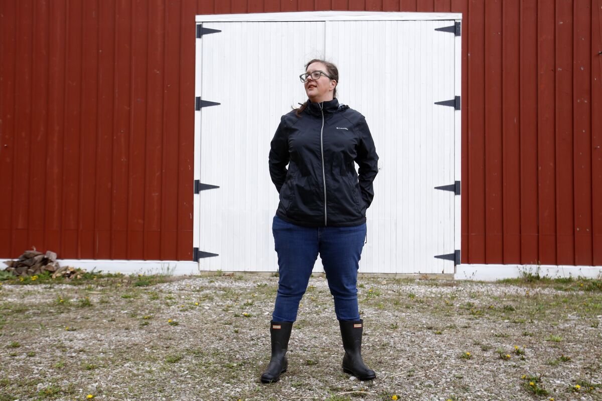 Alison Dreith stands in front of her barn in southern Illinois on Wednesday, April 13, 2022. Dreith works remotely for the Midwest Access Coalition, which pays for "practical support" for women seeking abortions. That includes things like air fare, gas money, hotel rooms or child care. Says Dreith, "I'm kind of a freak out first, calm down later kind of person is the big energy I have. So I really appreciate that I have something — no pun intended — like, really practical to do." (AP Photo/Martha Irvine)