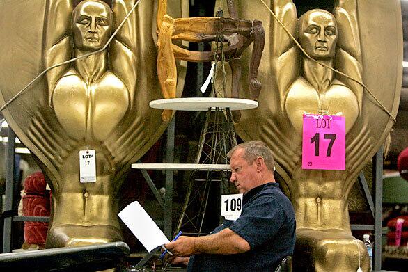 Brice Zellaer of Yuma checks a list of items that are part of the 20th Century Props auction Tuesday in North Hollywood. Behind him are golden angels with raised arms that were used in the motion picture "Anchorman" and television's "The Ellen Degeneres Show" and the "CSI" shows.