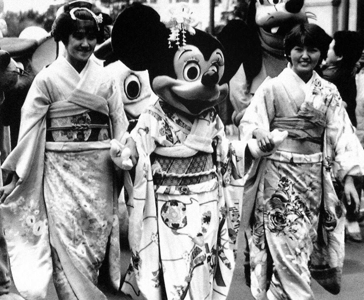 Dressed in kimono, Disney character Minnie Mouse walks hand in hand with two kimono-clad girls.