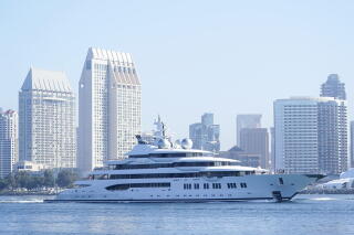 A huge yacht with a city skyline behind it.