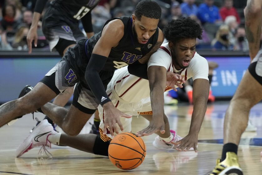 Washington's PJ Fuller, left, and Southern California's Joshua Morgan (24) scramble for the ball during the first half of an NCAA college basketball game in the quarterfinal round of the Pac-12 tournament Thursday, March 10, 2022, in Las Vegas. (AP Photo/John Locher)