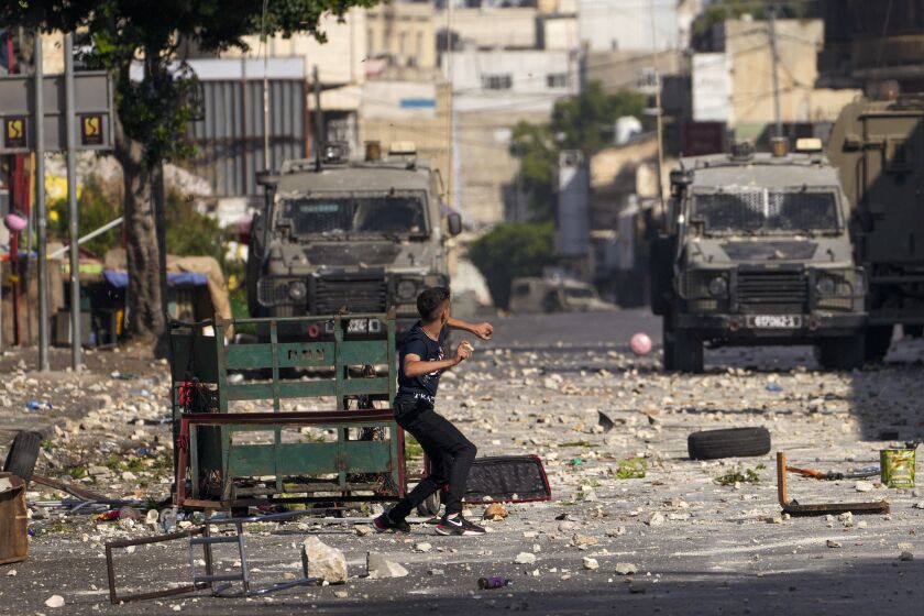 Palestinian demonstrators clash with the Israeli army while forces carry out an operation in the West Bank town of Nablus, Tuesday, Aug. 9, 2022. Israeli police said forces encircled the home of Ibrahim al-Nabulsi, who they say was wanted for a string of shootings in the West Bank earlier this year. They said al-Nabulsi and another Palestinian militant were killed in a shootout at the scene, and that troops found arms and explosives in his home. (AP Photo/Majdi Mohammed)
