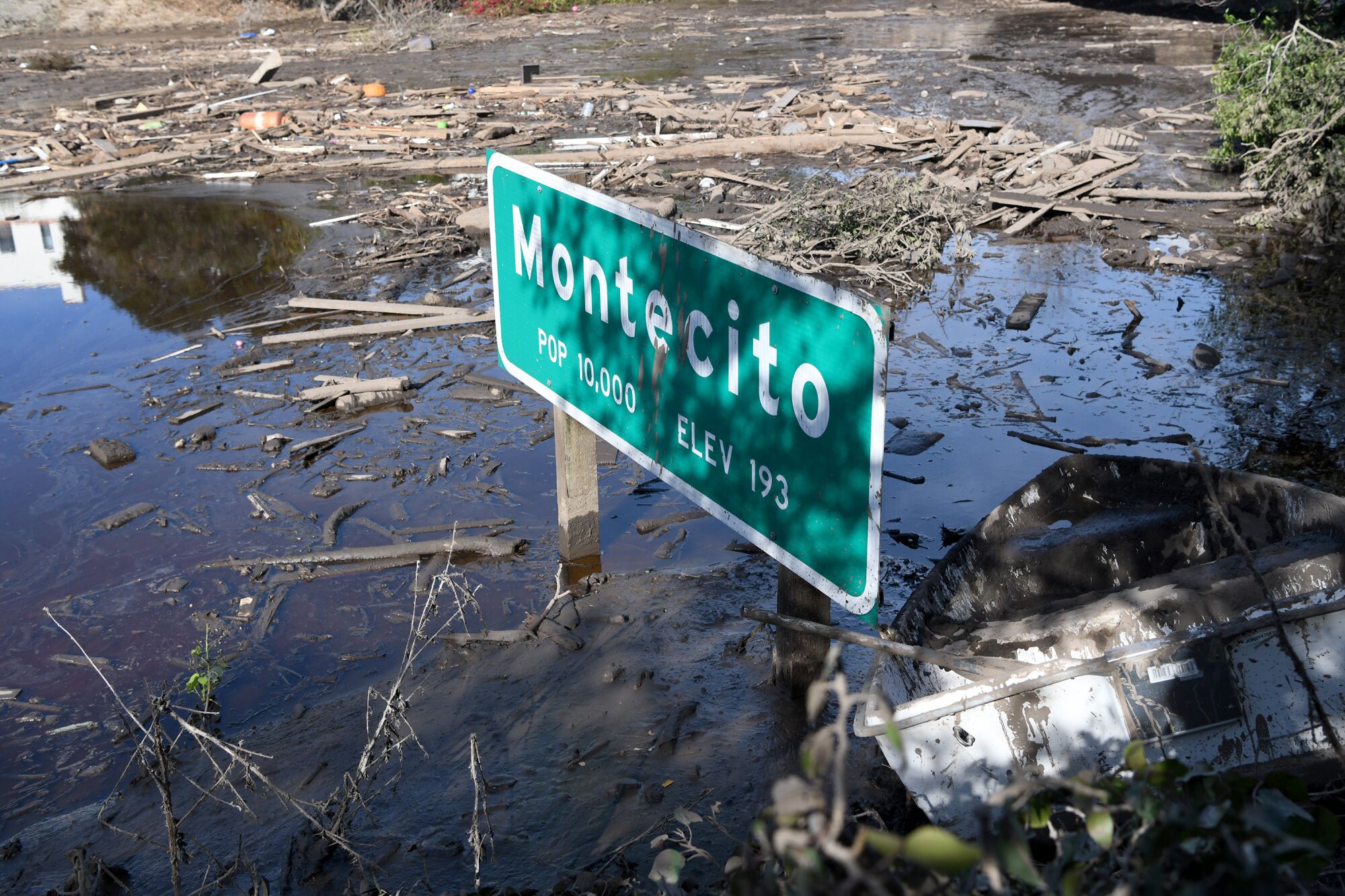 Water and mud surround a sign listing Montecito's population and elevation 