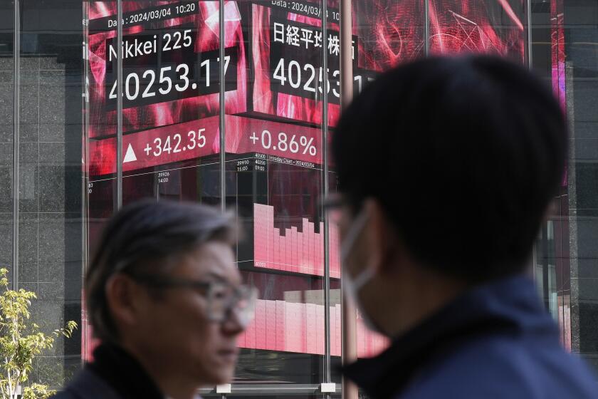 People walk in front of an electronic stock board showing Japan's Nikkei 225 index at a securities firm Monday, March 4, 2024, in Tokyo. Japan's Nikkei 225 share benchmark has topped 40,000 for the first time as strong demand for technology shares keeps pushing the index higher.(AP Photo/Eugene Hoshiko)