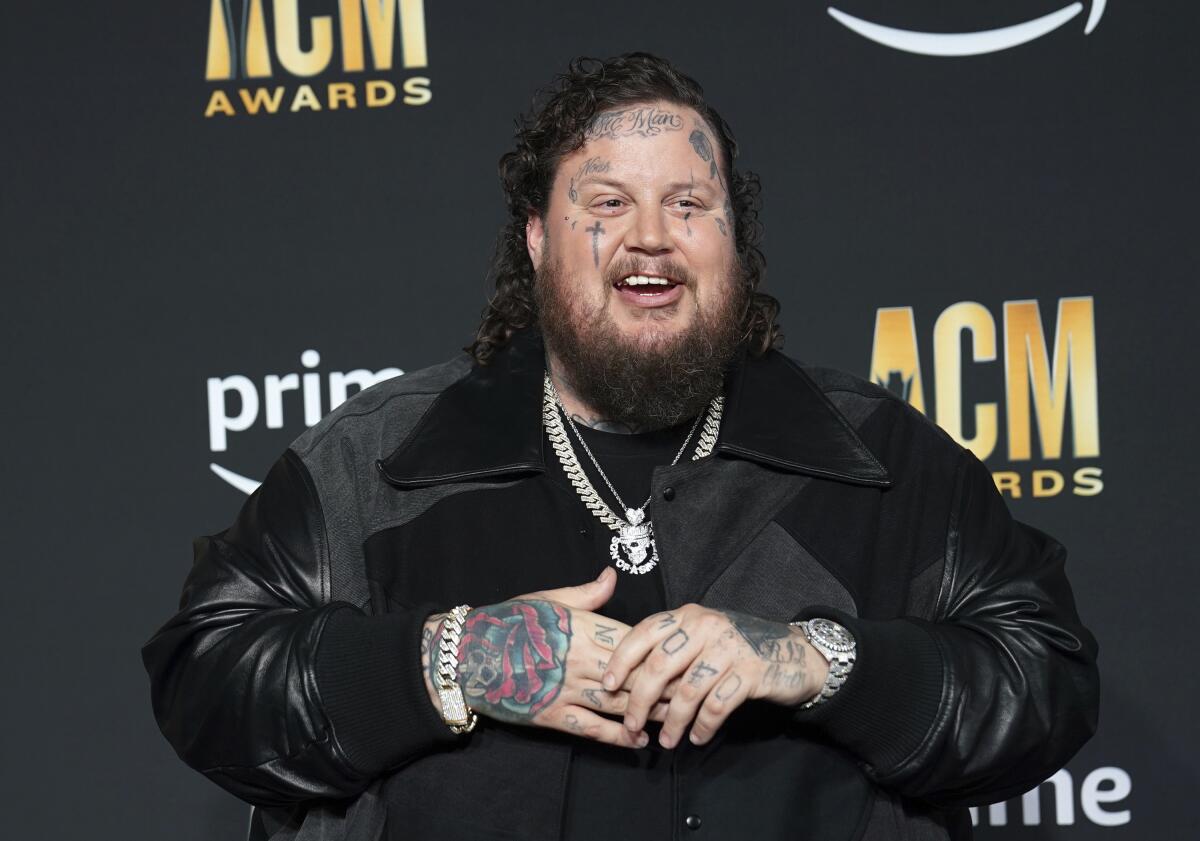 Bearded musician Jelly Roll smiles while arriving at an awards show