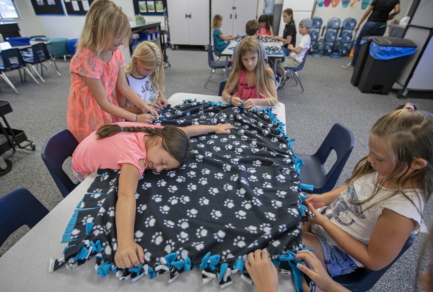 Zoe Presutto, 8, left, lies on a blanket at the YMCA child care at Agnes L. Smith Elementary School in Huntington Beach on Friday. She and other participants in the program made blankets for local animal shelters as part of the YMCA of Orange County program "100 Acts of Kindness."