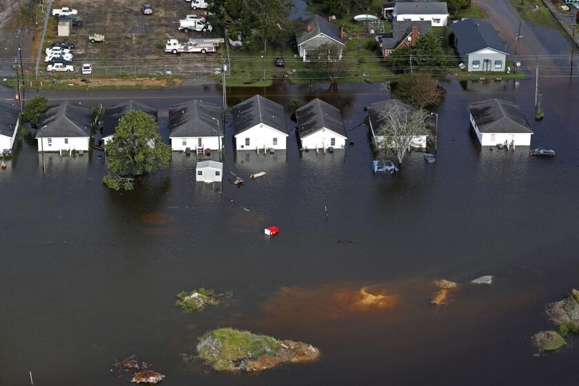 FILE - In this Monday, Sept. 17, 2018 file photo, floodwaters from Hurricane Florence surrounds homes in Dillon, S.C. Scientists say climate change likely boosted rainfall totals for both Florence and 2017's Harvey. (AP Photo/Gerald Herbert)