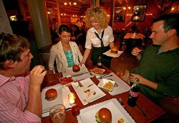 Waitress Winslow Corbett serves burgers to patrons at Umami Burger in Los Feliz.