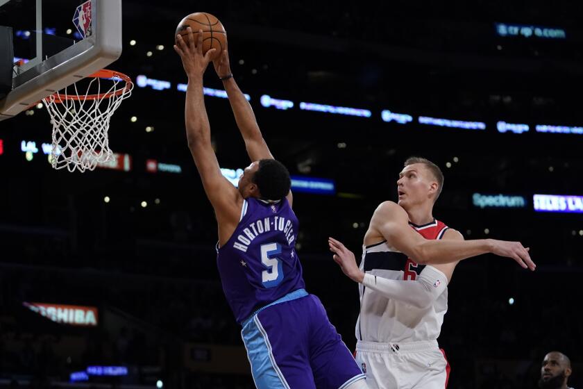 Los Angeles Lakers guard Talen Horton-Tucker (5) dunks against Washington Wizards center Kristaps Porzingis (6) during the first half of an NBA basketball game in Los Angeles, Friday, March 11, 2022. (AP Photo/Ashley Landis)