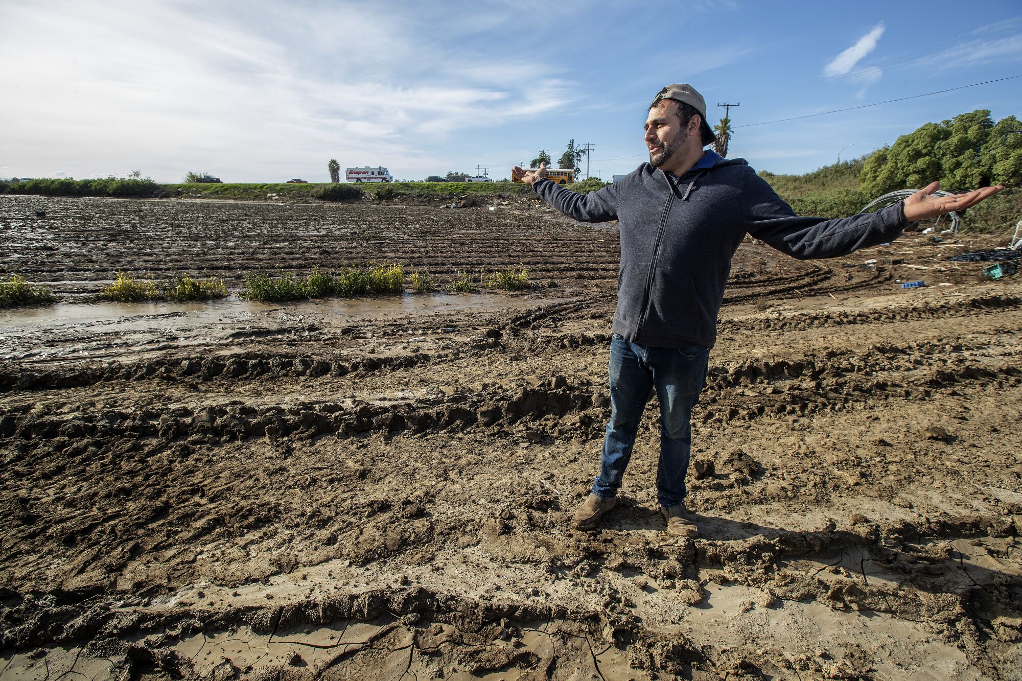 A main speads his arms while standing in a muddy field.