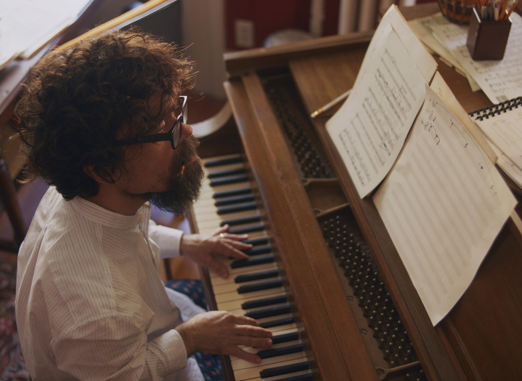 A bearded man plays piano.
