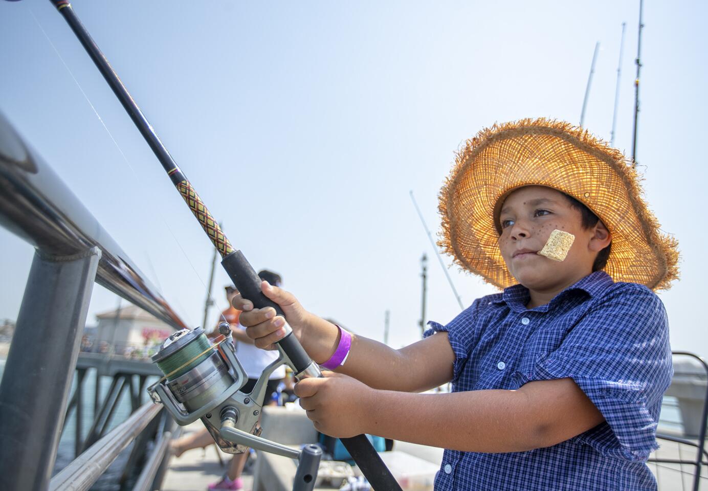 Elijah Rothert, 8, fishes from the Huntington Beach Pier during the 55th annual Huck Finn Fishing Derby on Saturday, August 11.