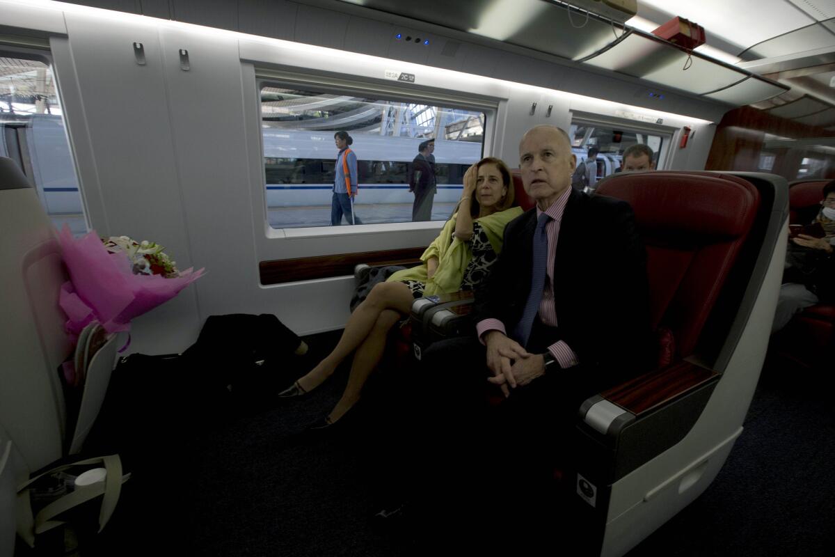 California Gov. Jerry Brown, center, and his wife, Anne Brown, sit onboard a high-speed rail train leaving from the Beijing South train station in China.