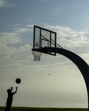 A boy throws a basketball into a hoop
