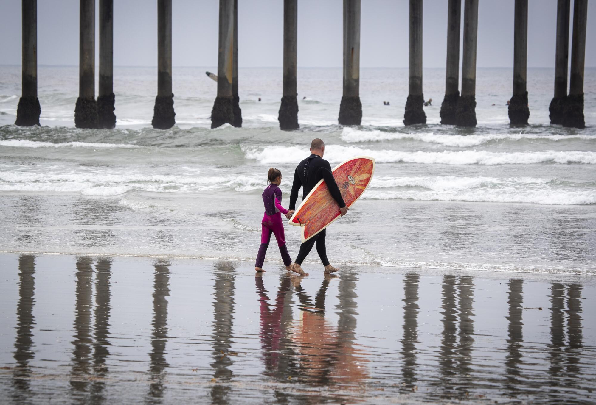  Beachgoers hold hands while heading out to surf 