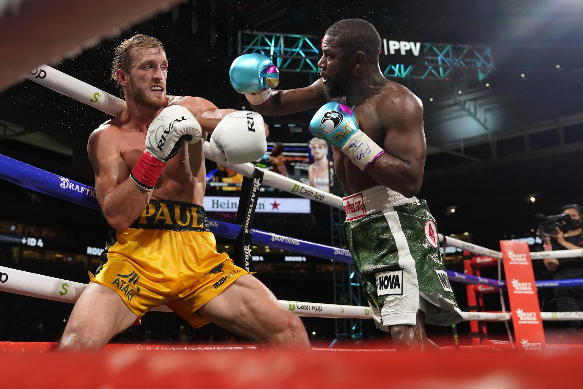 Floyd Mayweather, right, throws a punch at Logan Paul