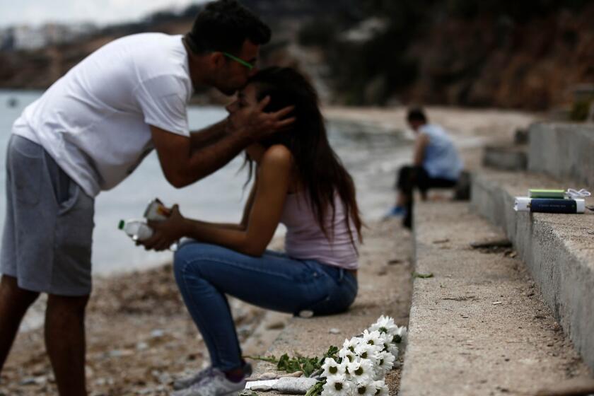 Mandatory Credit: Photo by YANNIS KOLESIDIS/EPA-EFE/REX/Shutterstock (9772189b) Dimitris Matrakidis kisses his sister Maria, as flowers are placed at the point where a six month baby died, following a deadly forest fire in Mati, a northeast suburb of Athens, Greece, 27 July 2018. The confirmed death toll from forest fires that raged through seaside resorts near the Greek capital Athens has increased to 87. According to an announcement by Fire Brigade, the search for more missing persons in the burnt out buildings in eastern Attica is continuing. Aftermath of deadly wildfires near Athens, Greece - 27 Jul 2018 ** Usable by LA, CT and MoD ONLY **