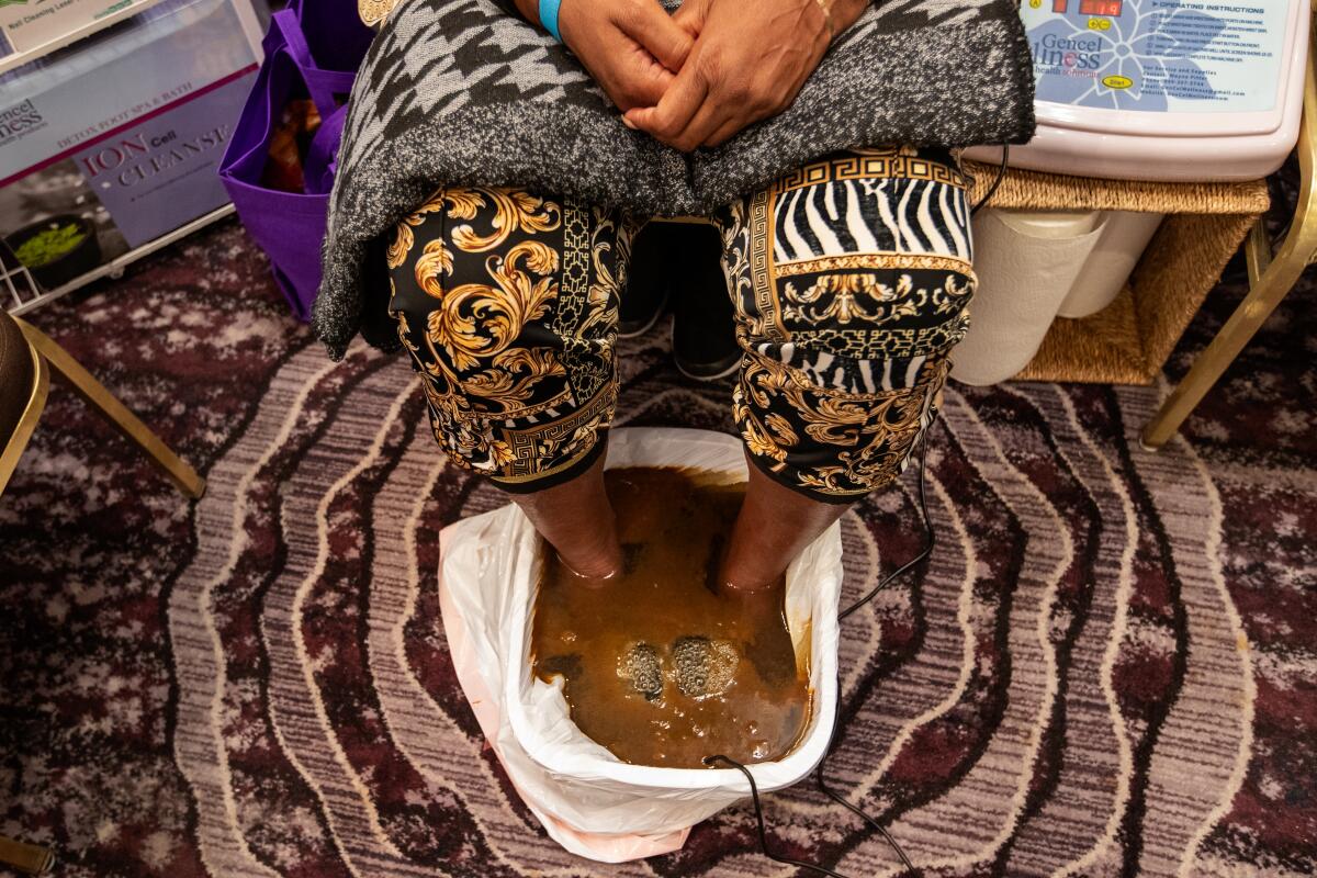 A woman soaks her feet in murky brown liquid.