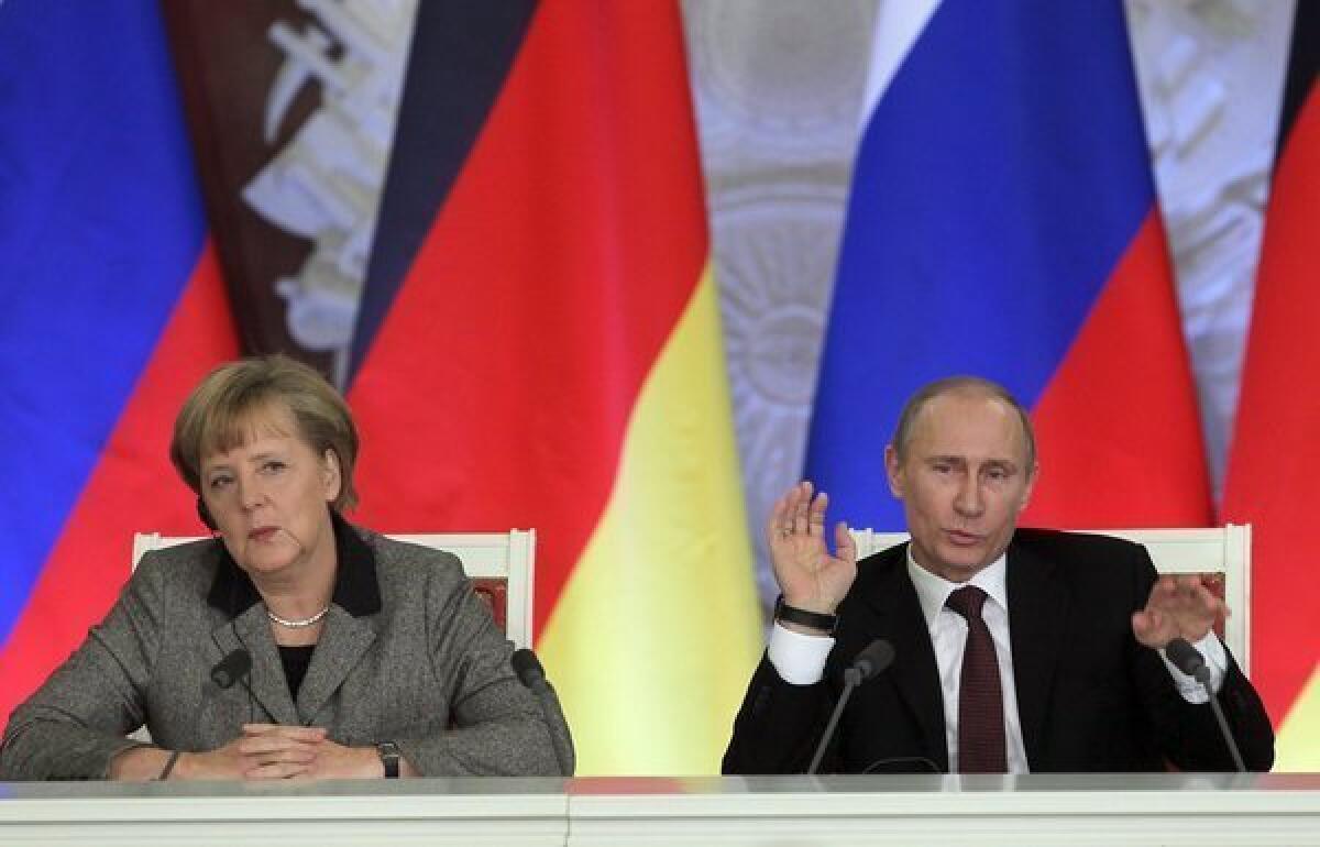 German Chancellor Angela Merkel, left, and Russian President Vladimir Putin speak at a news conference after the 14th German-Russian inter-governmental consultations at the Kremlin in Moscow.