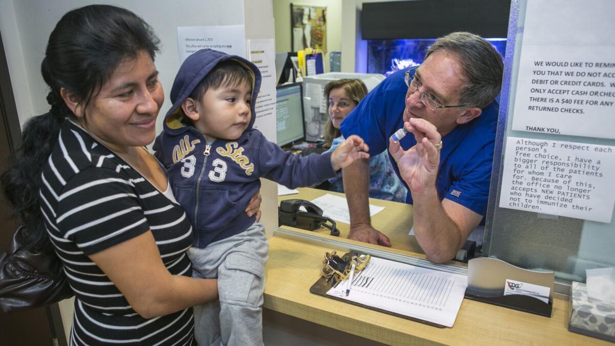 Charles Goodman talks with patient Carmen Lopez, 37, holding her 18-month-old son, Daniel, after being vaccinated with the measles-mumps-rubella vaccine, or MMR, at his practice in Northridge.