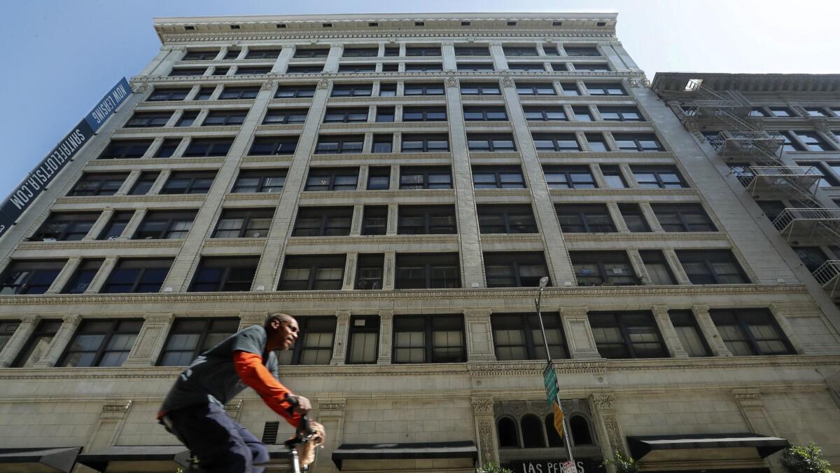 A bicycle rider pedals along 6th Street in downtown Los Angeles, past the Santa Fe Lofts building. The property just sold for nearly $70 million, part of the transformation of downtown in recent years that has been accompanied by rising rents.