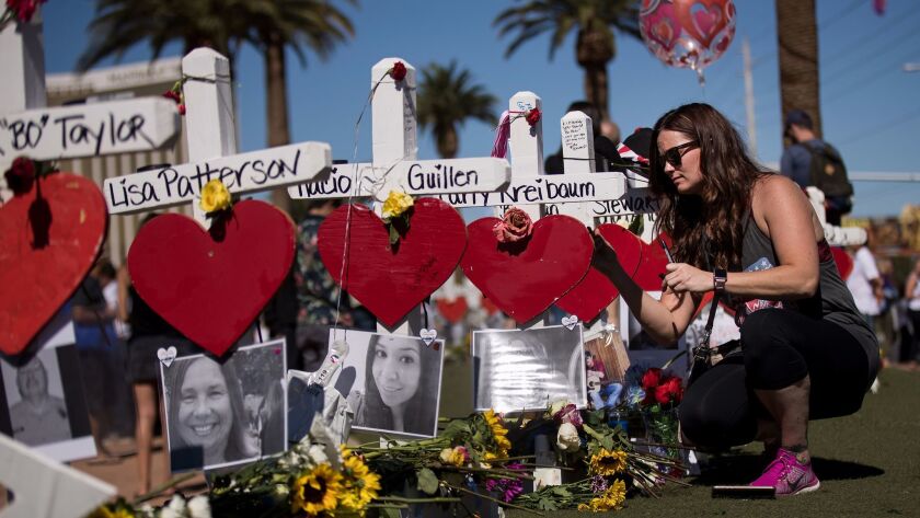 A visitor writes a note on a cross for Carly Kreibaum, who was killed in the Oct. 1 Las Vegas massacre, at a makeshift memorial for the 58 slain victims.