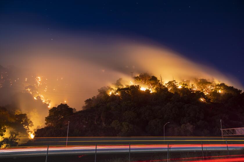 NEWHLL, CALIF. -- FRIDAY, OCTOBER 11, 2019: Traffic moves slowly as the Saddleridge fire flares up in the hills along the I-5 Freeway in the Newhall Pass, which was opened in both directions late Friday, while the fire continued to make a destructive march in the northern foothills of the San Fernando Valley, burning numerous homes near Newhall Friday, Oct. 11, 2019. (Allen J. Schaben / Los Angeles Times)