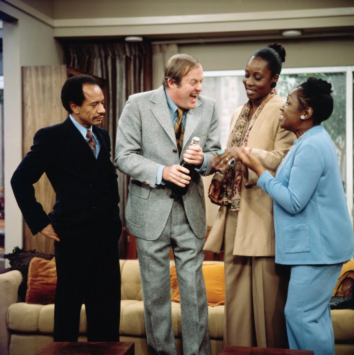 Two men and two women standing in a living room laughing.