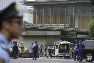 Police officers work near a vehicle, center, which was stuck against a barricade near the prime minister's office, background, in Tokyo Saturday, Oct. 19, 2024. (Kyodo News via AP)