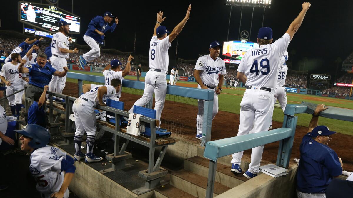 Dodgers jump from their dugout seats as Enrique Hernandez hits an RBI single in the tenth inning to tie the score at 5 in Game two of the World Series at Dodger Stadium.