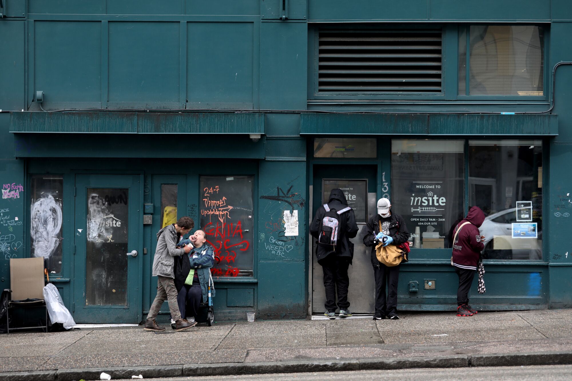 People wait on a sidewalk outside a business