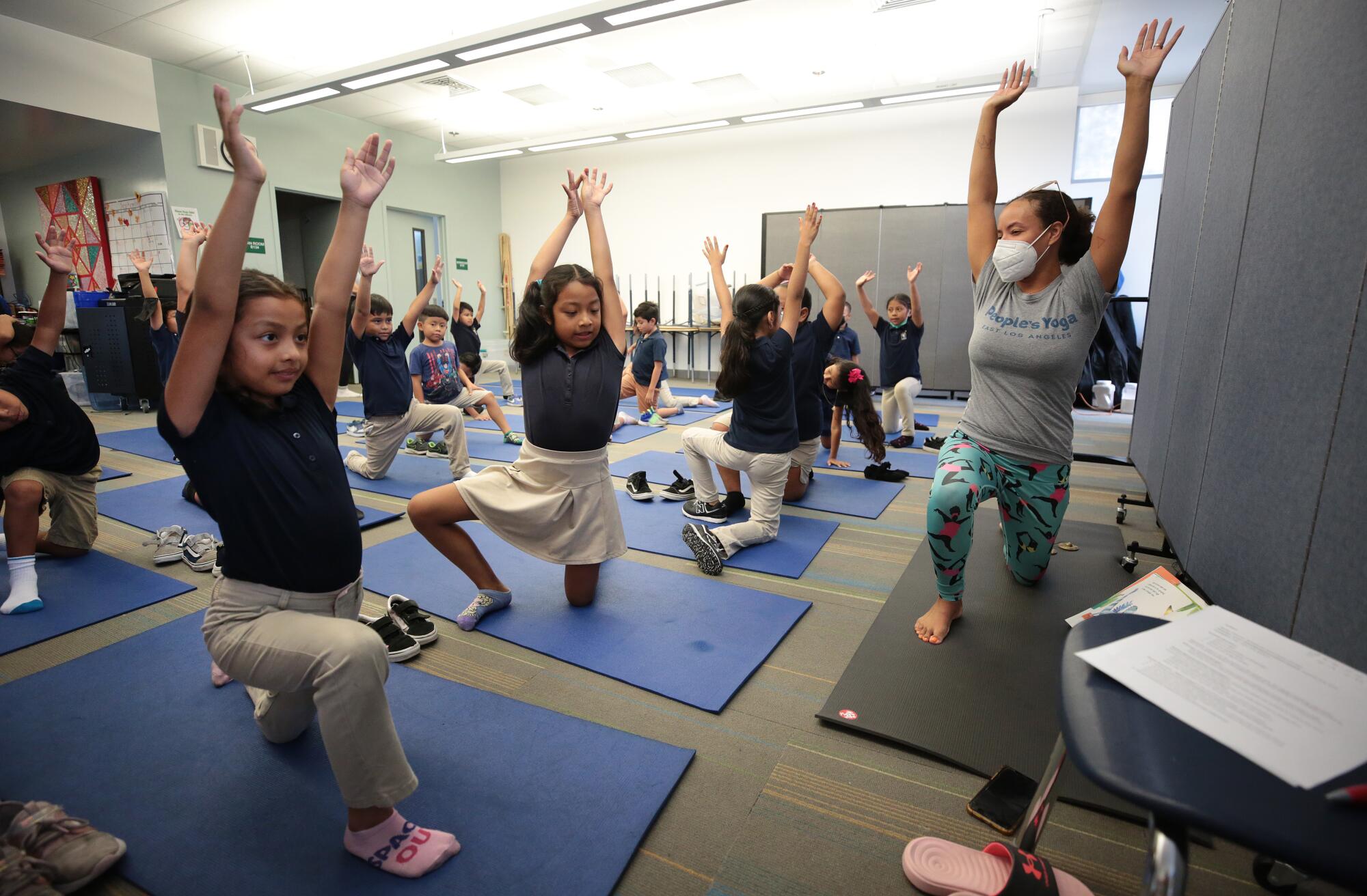 Second grade students Sophia Galarza, Jasmine Saloj and Giselle Calderon stretch to instructions from Yoga instructors
